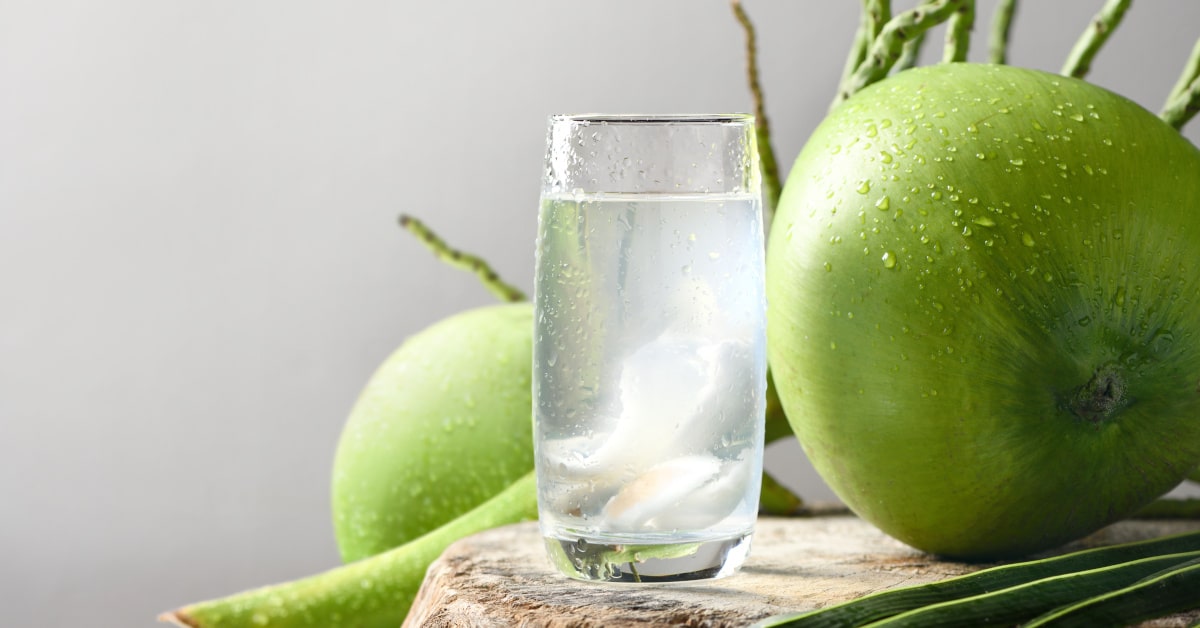 Acqua di cocco in bicchiere e noce di cocco verde